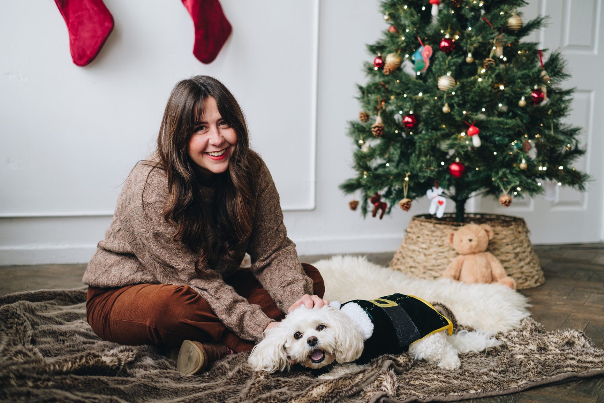 Woman and dog sat by a Christmas tree