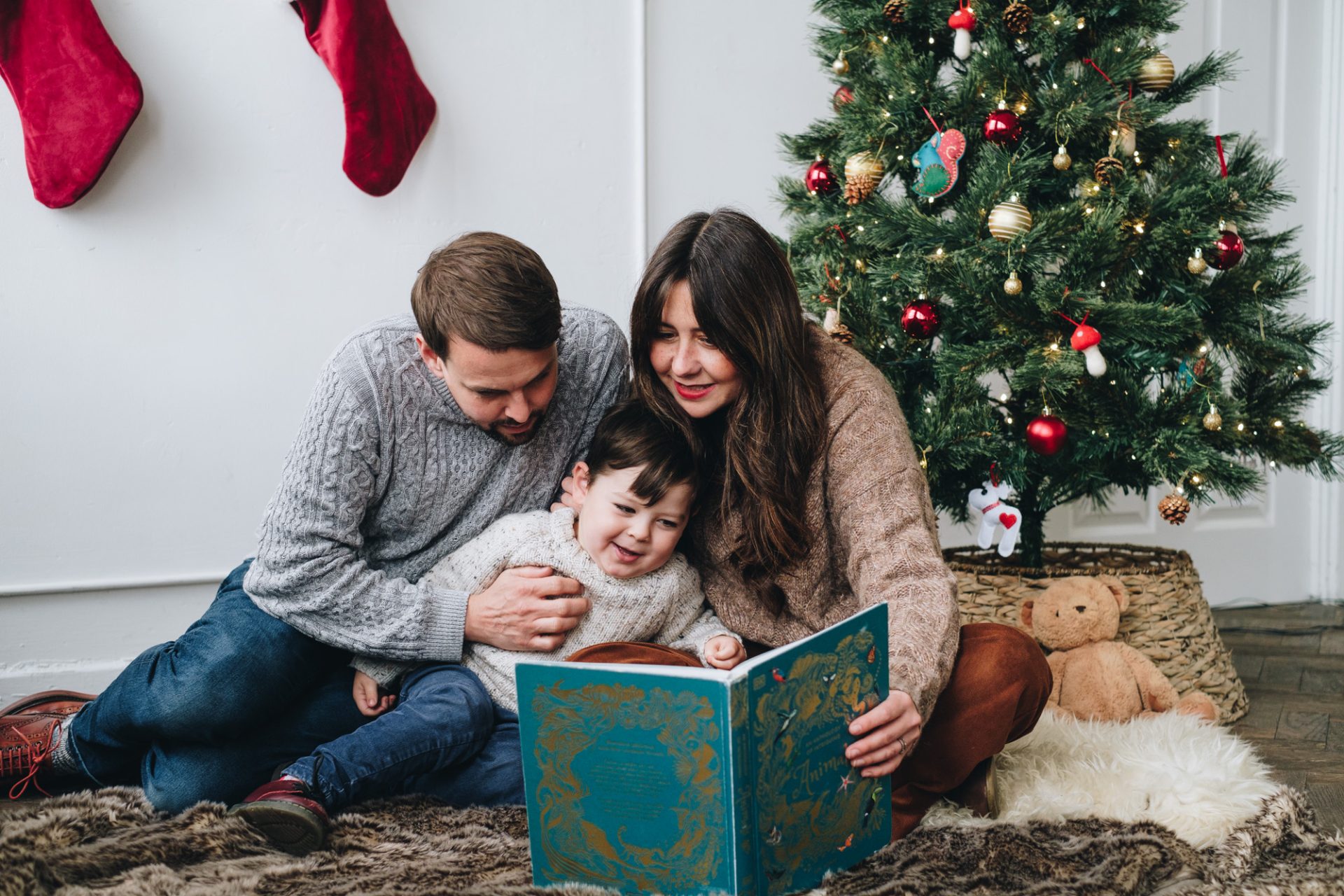 Family reading a story by a Christmas tree during a photoshoot in Sheffield