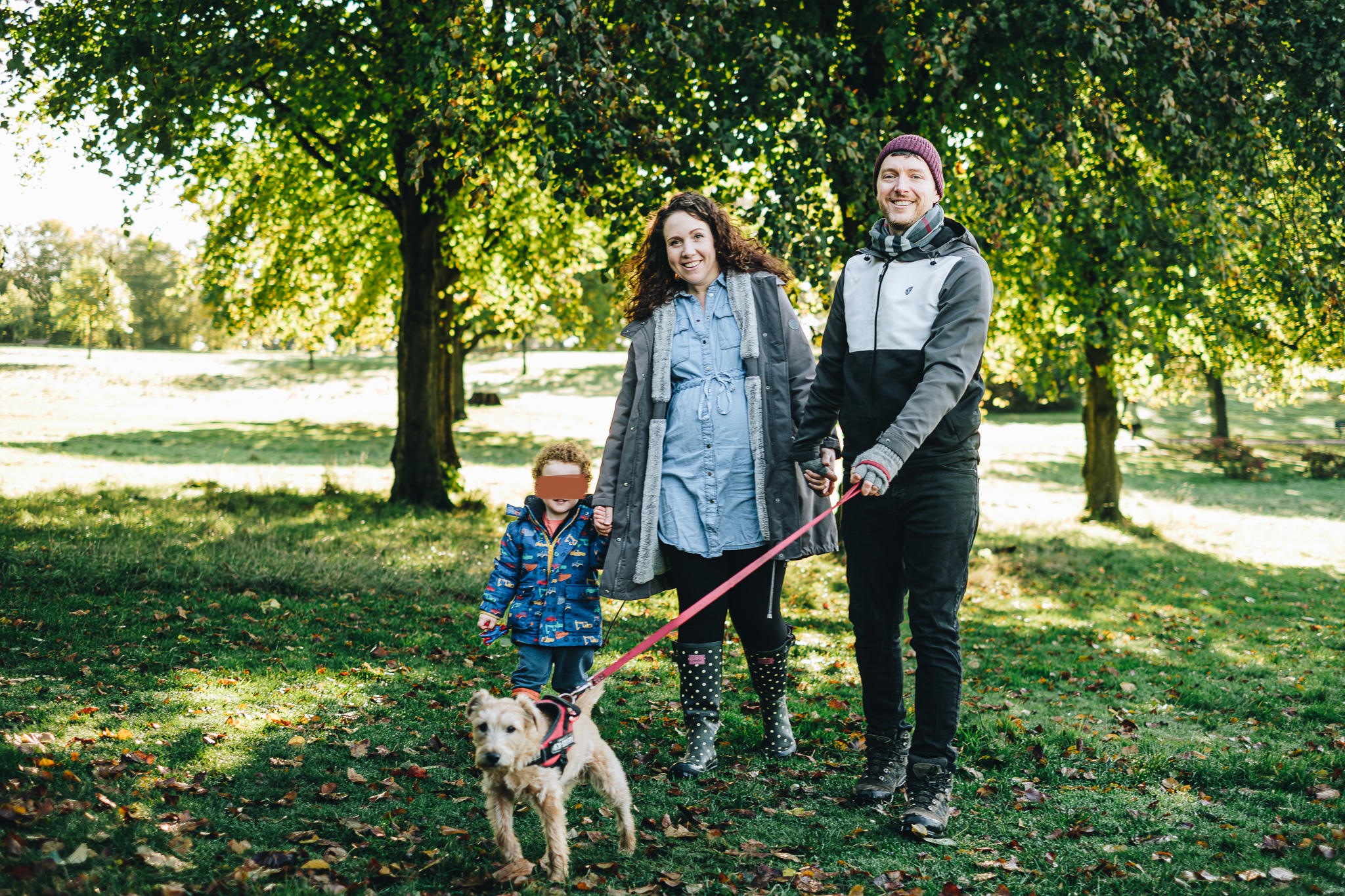 Family smiles at camera while walking their dog in Graves Park