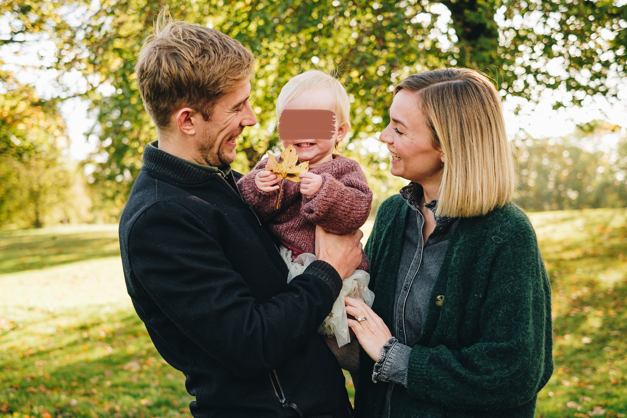 Mum and Dad look at their daughter, between them, smiling.