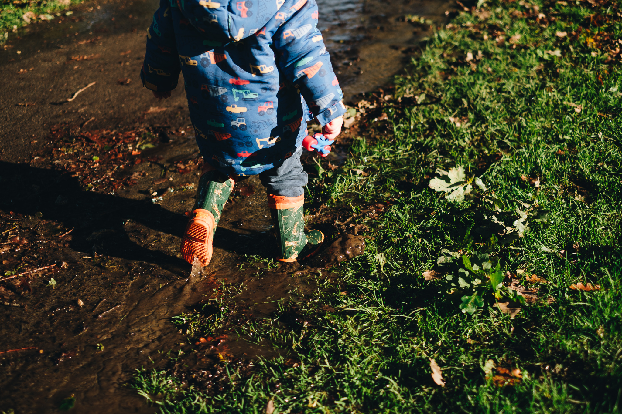 Child's wellies splashing in a mud puddle