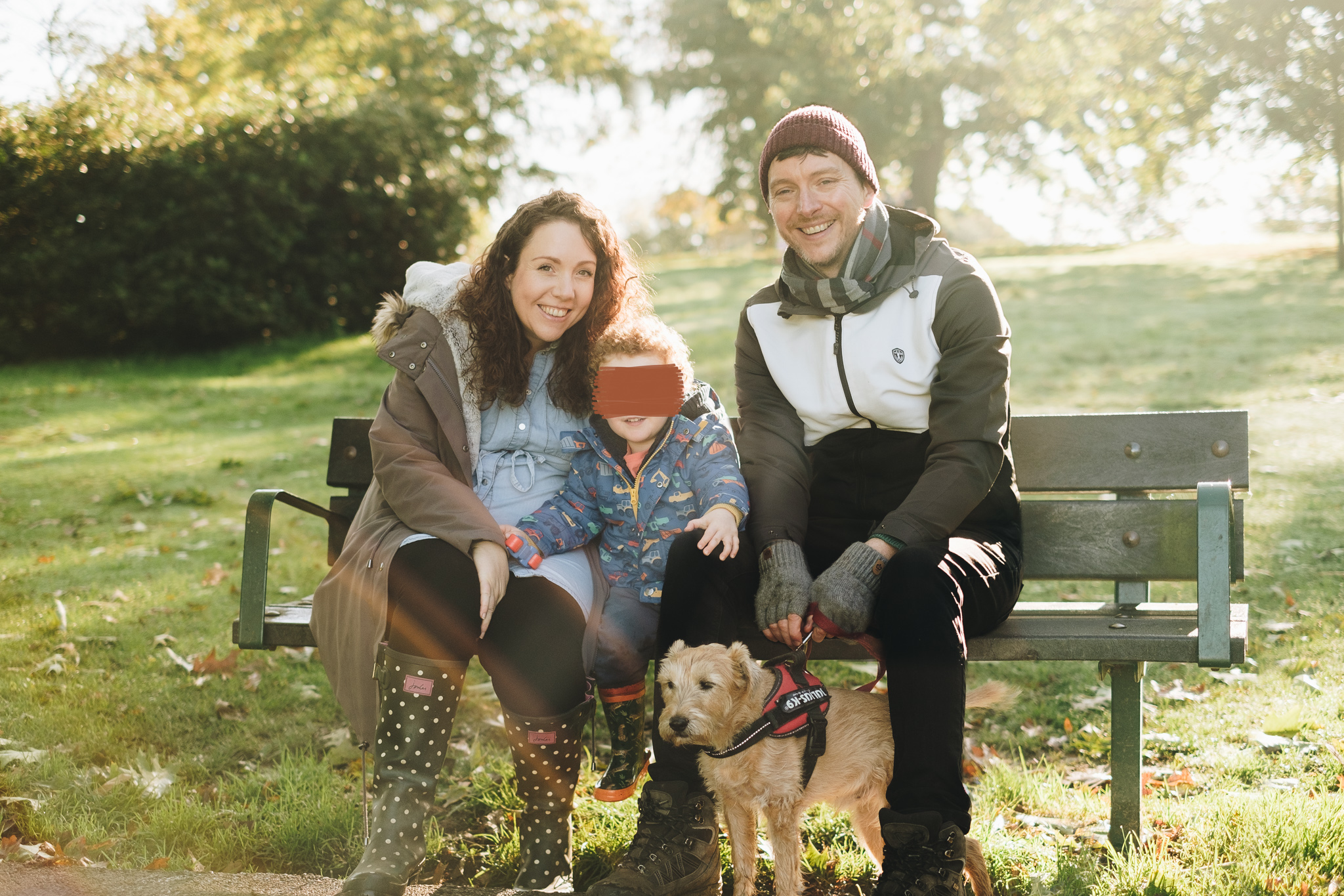 Family sat on bench smiling with their dog