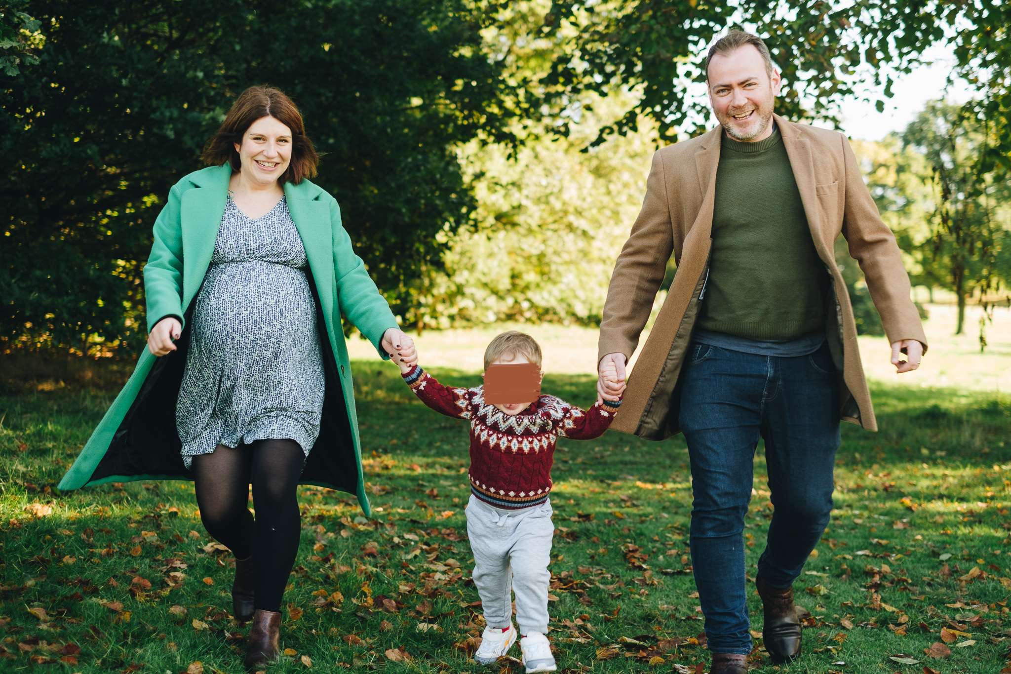 Family holding hands walking towards the camera, smiling