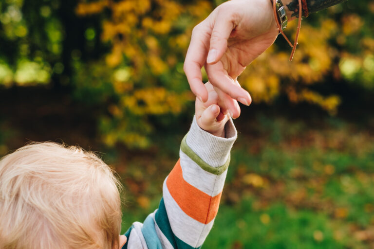 Close up of mum and child holding hands