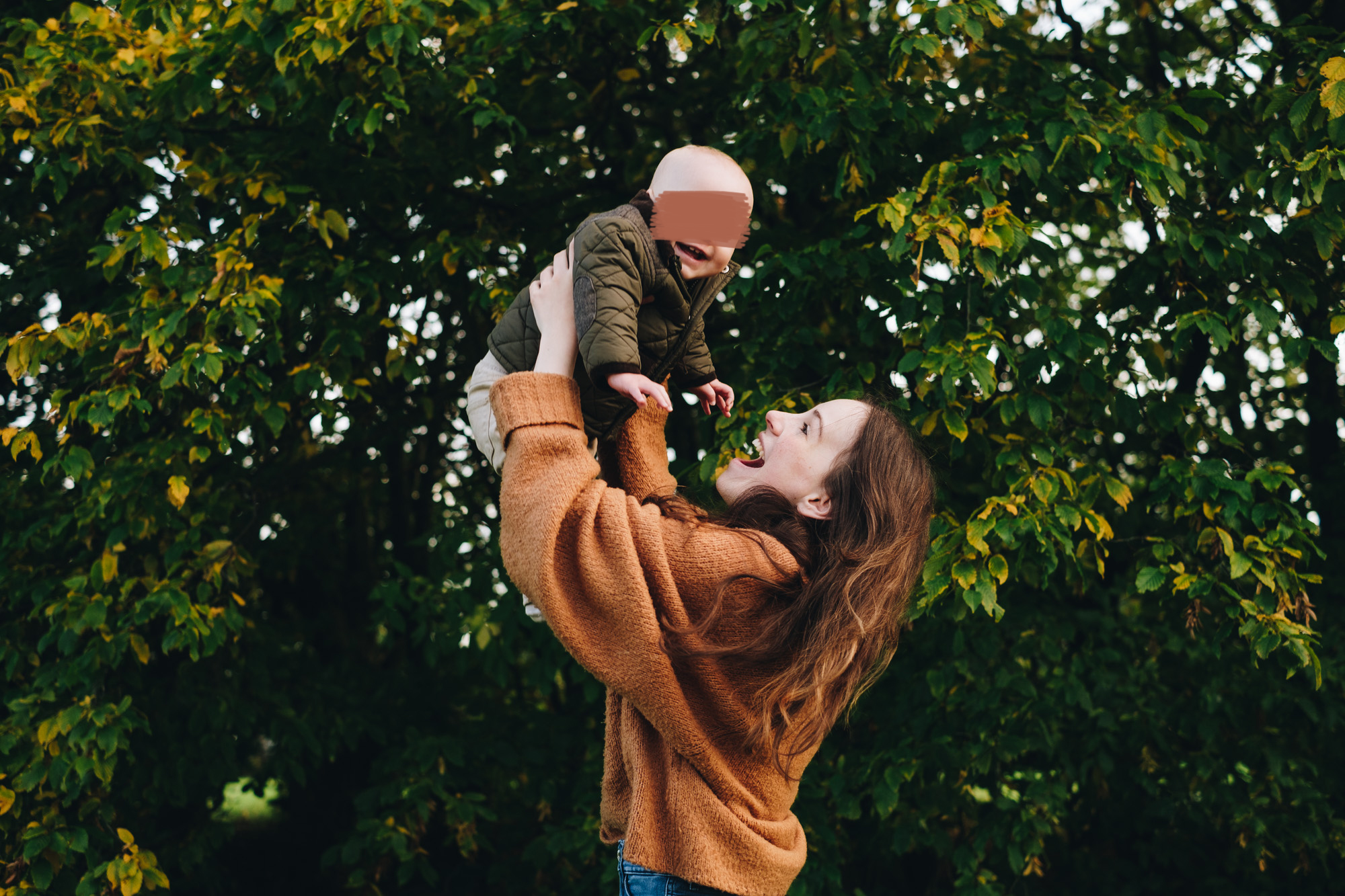 Mum lifts her baby over her head, both laughing